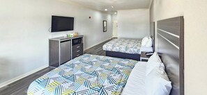 Una habitación de hotel con dos camas, televisión, escritorio y armario.