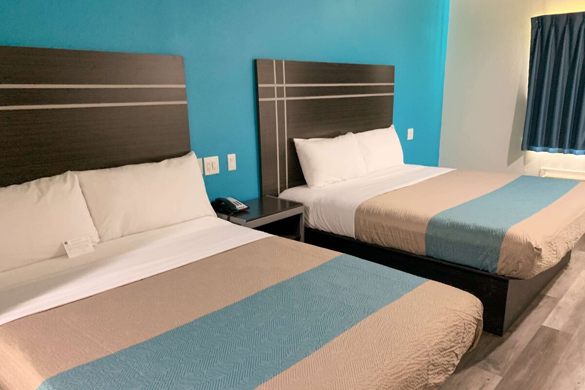 Two twin beds with headboards, a bedside table with a phone, and a window with curtains.