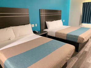 Two twin beds with headboards, a bedside table with a phone, and a window with curtains.