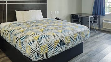 Een hotelkamer met een bed, een bureau, een stoel en een raam met gordijnen.