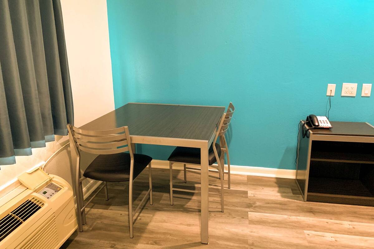 A room with a table and two chairs, a heater, a telephone, and a wall socket.