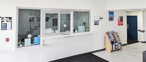 A reception area with a window, a bulletin board, and a check-out counter.
