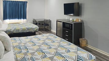 Ein Hotelzimmer mit zwei Betten, einem Schreibtisch, einem Fernseher und einem Schrank.