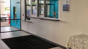 A hotel lobby with a glass door entrance, a black carpet, and a small table with a white tablecloth. - Motel 6 Houston, TX - Hwy 249 and Fallbrook (Houston)