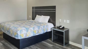 Una habitación de hotel con cama, mesita de noche y escritorio.