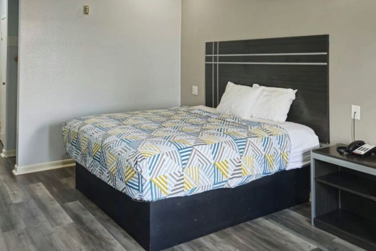 A hotel room with a bed, a bedside table, and a telephone.