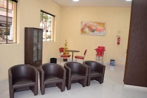 A room with four brown chairs, a small table with a vase, a cabinet, and a painting on the wall. - Hotel Calstar (Sao Paulo)