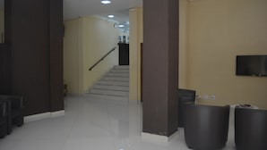 Un vestíbul modern i net, amb una escala, un televisor de pantalla plana penjat a la paret i una recepció.