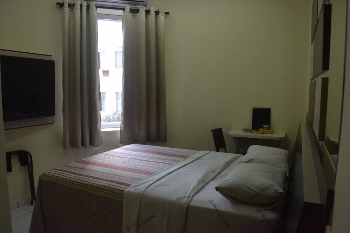 Ein Hotelzimmer mit einem Bett, einem Fernseher, einem kleinen Tisch und einem Sessel.