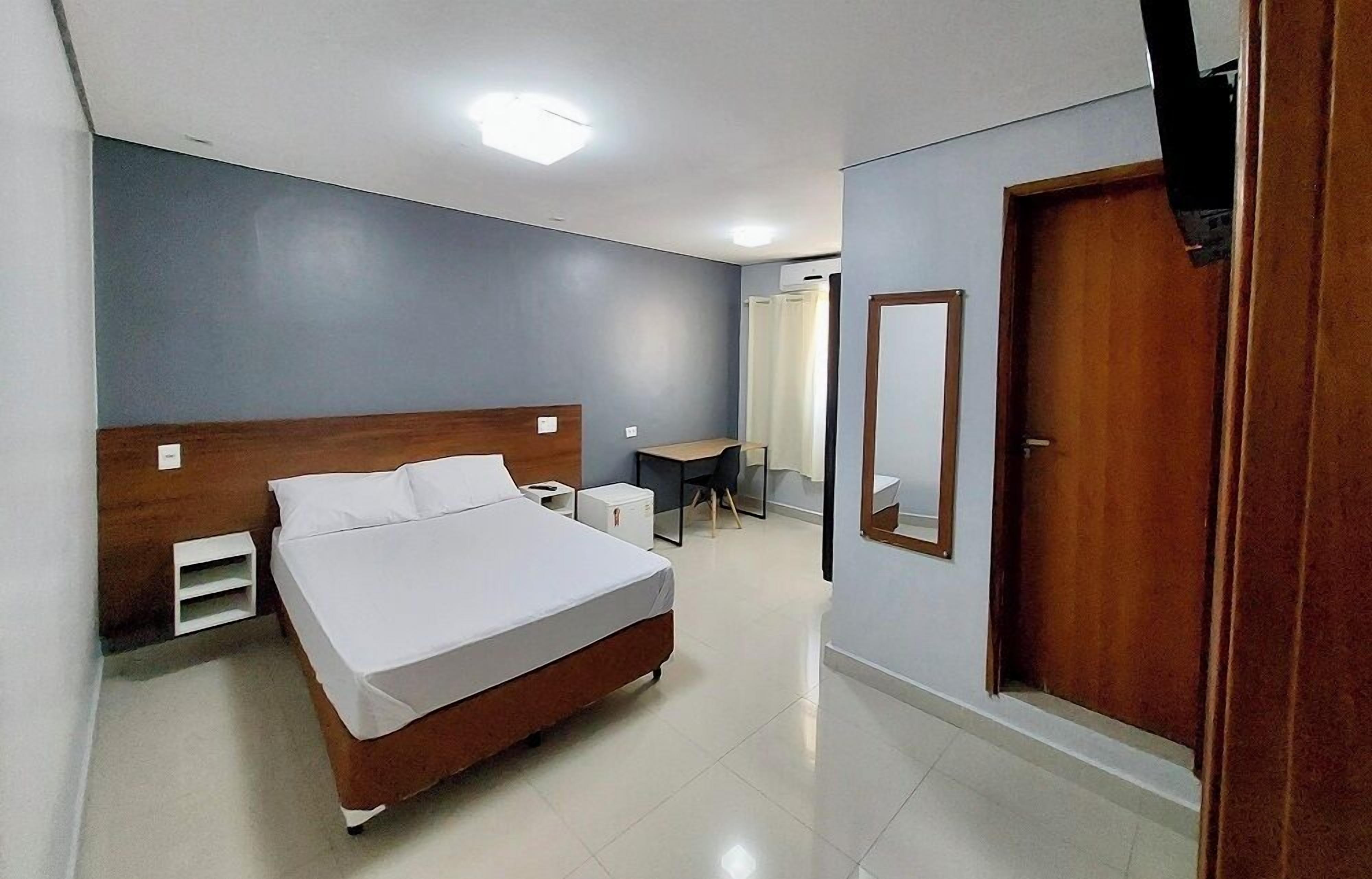 A bedroom with a bed, bedside tables, a desk, and a wardrobe.