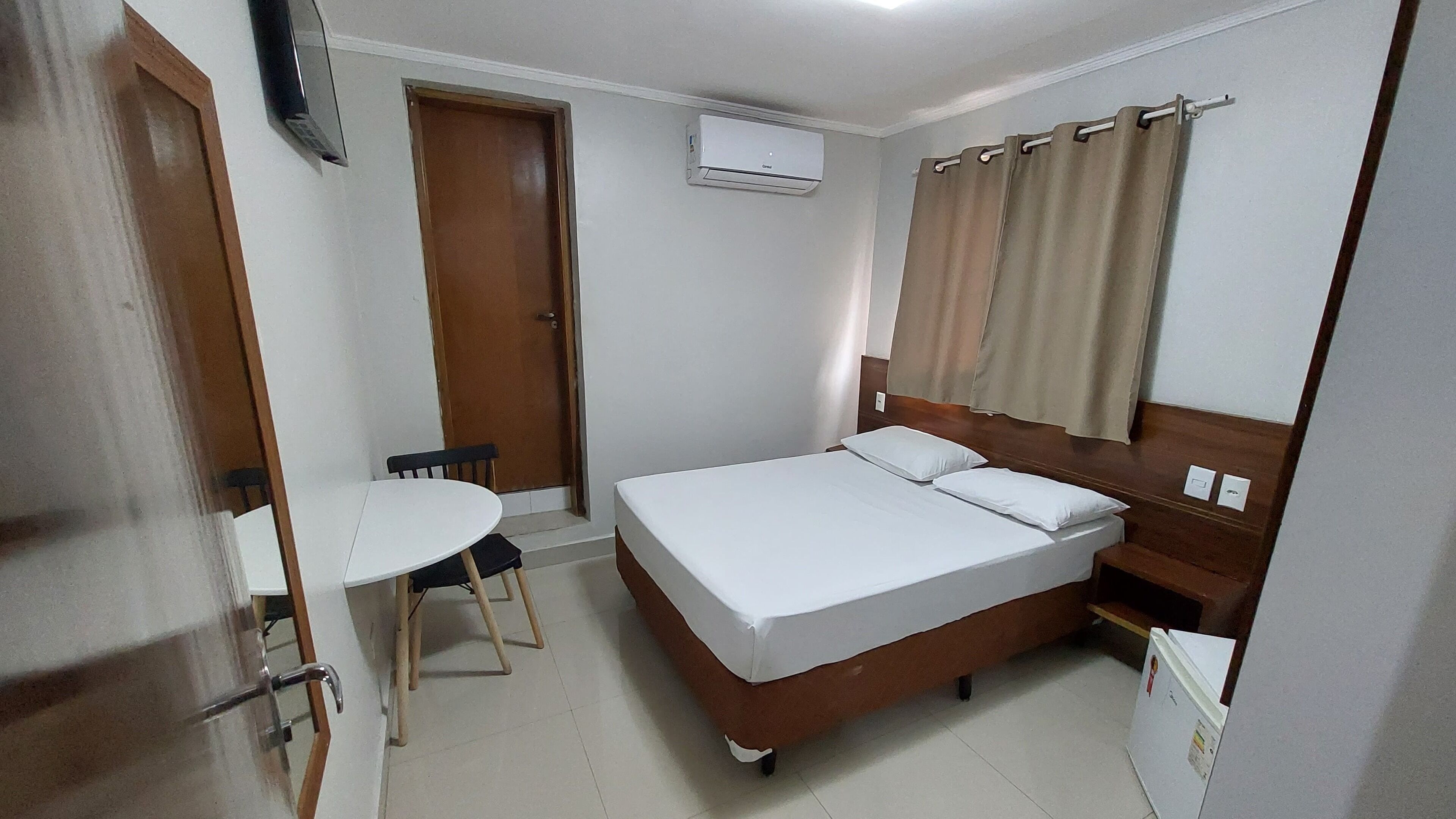 Una habitación pequeña y limpia con una cama individual, una mesa y una silla.