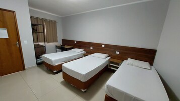 Una habitación con tres camas individuales, un escritorio, una silla y un armario.