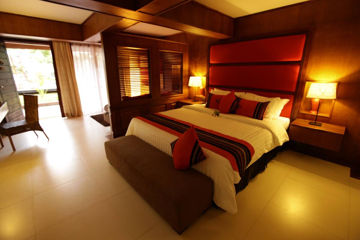 Une chambre spacieuse avec un grand lit, une tête de lit en bois et deux lampes de chevet.