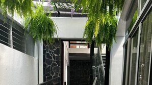 Um corredor externo moderno com parede de pedra, guarda-corpo de metal e vegetação.
