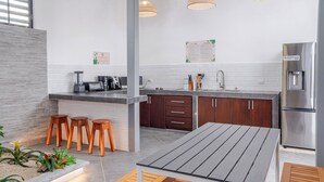 Uma cozinha moderna com área de bar, banquetas de madeira, mesa de jantar e geladeira.