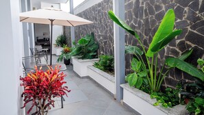 Um interior moderno com parede de pedra, plantas de interior e área de refeições com cadeiras e uma mesa.