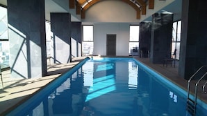 Una piscina interior con agua cristalina, una extensión considerable y vistas de la ciudad a través de amplios ventanales.