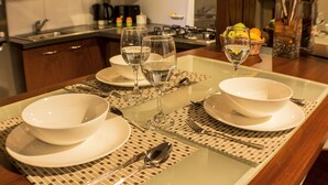 Una mesa de comedor dispuesta con platos, tazones y cubiertos blancos, y una servilleta debajo.
