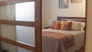 Una habitación de hotel con una cama, una mesita de noche, una lámpara y una pared con un cuadro enmarcado.
