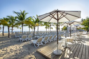 På stranden, vit sandstrand, solstolar och strandhanddukar
