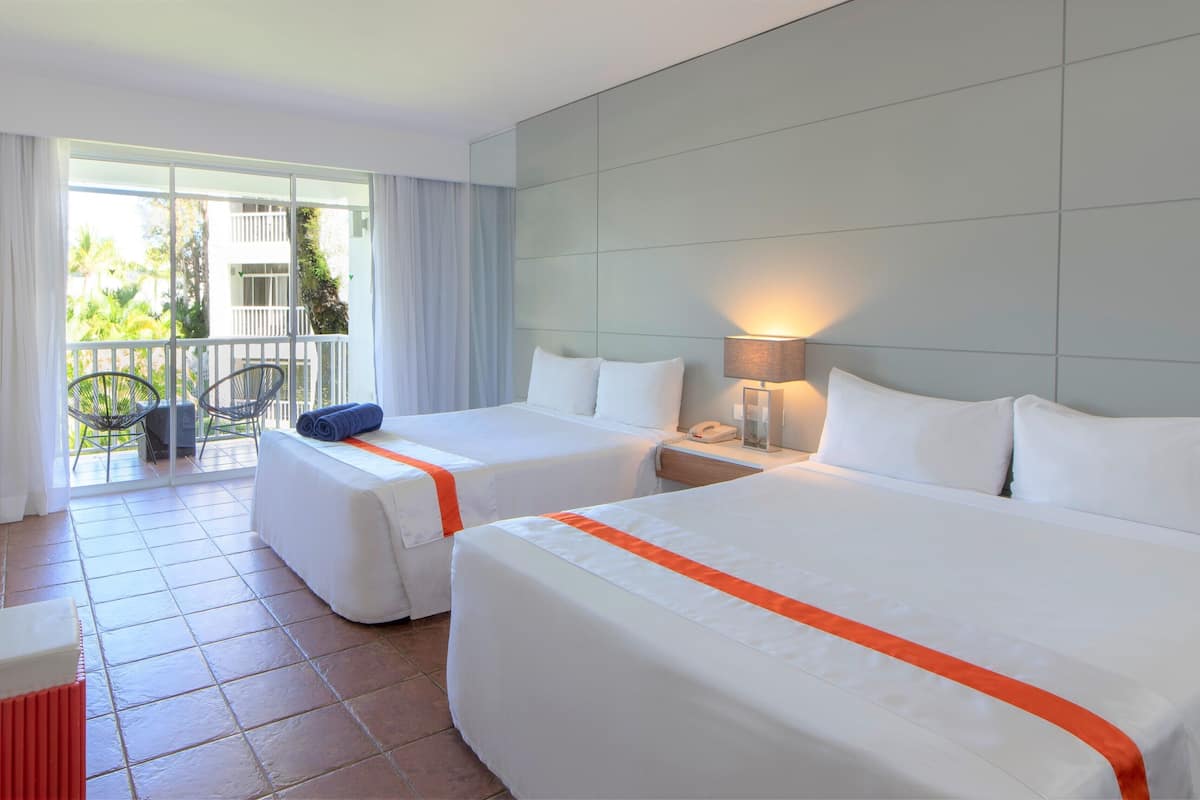 Une chambre d’hôtel avec deux lits, un balcon avec des chaises et une vue sur l’extérieur.
