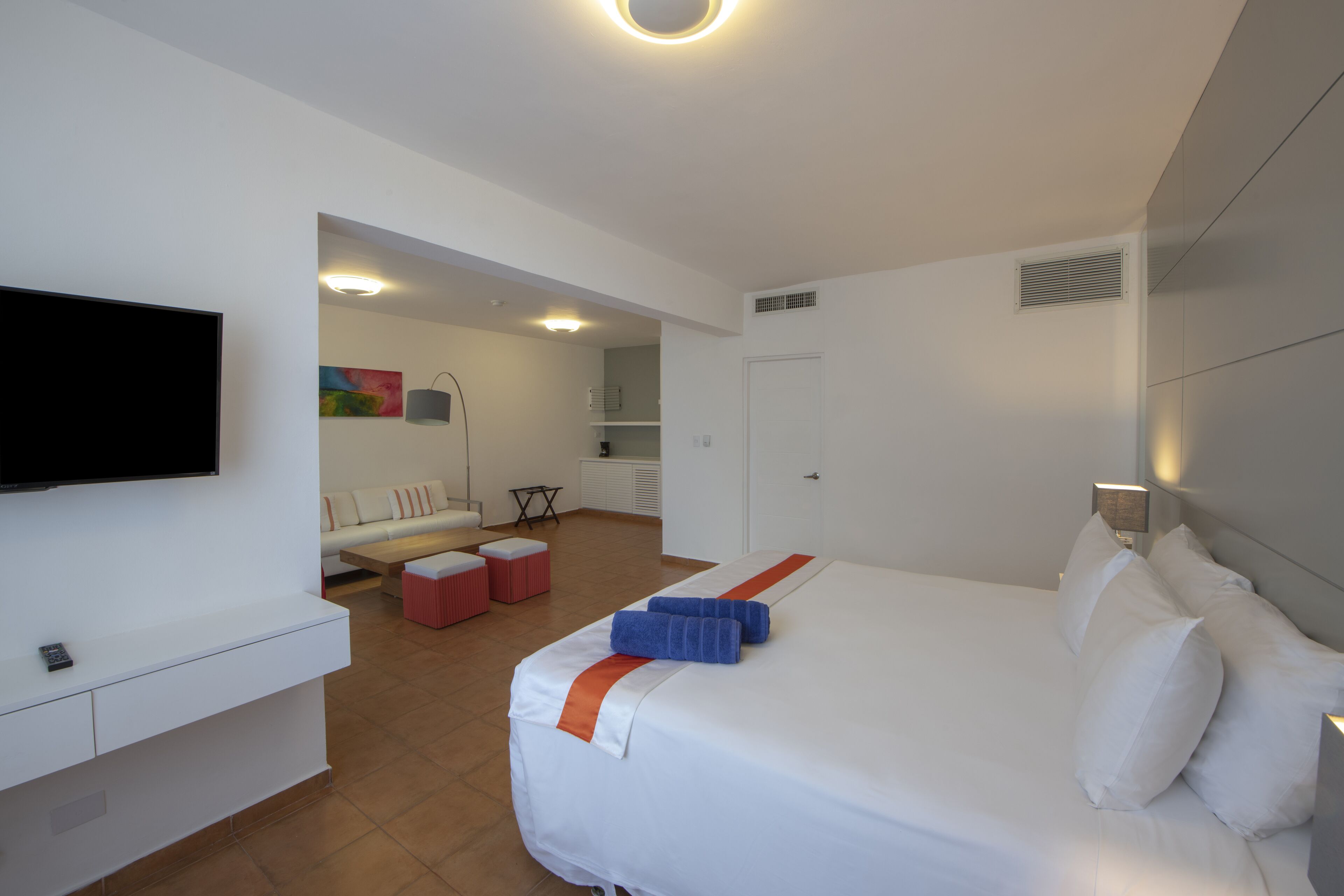 A hotel room with a bed, a TV, a desk, and a seating area.