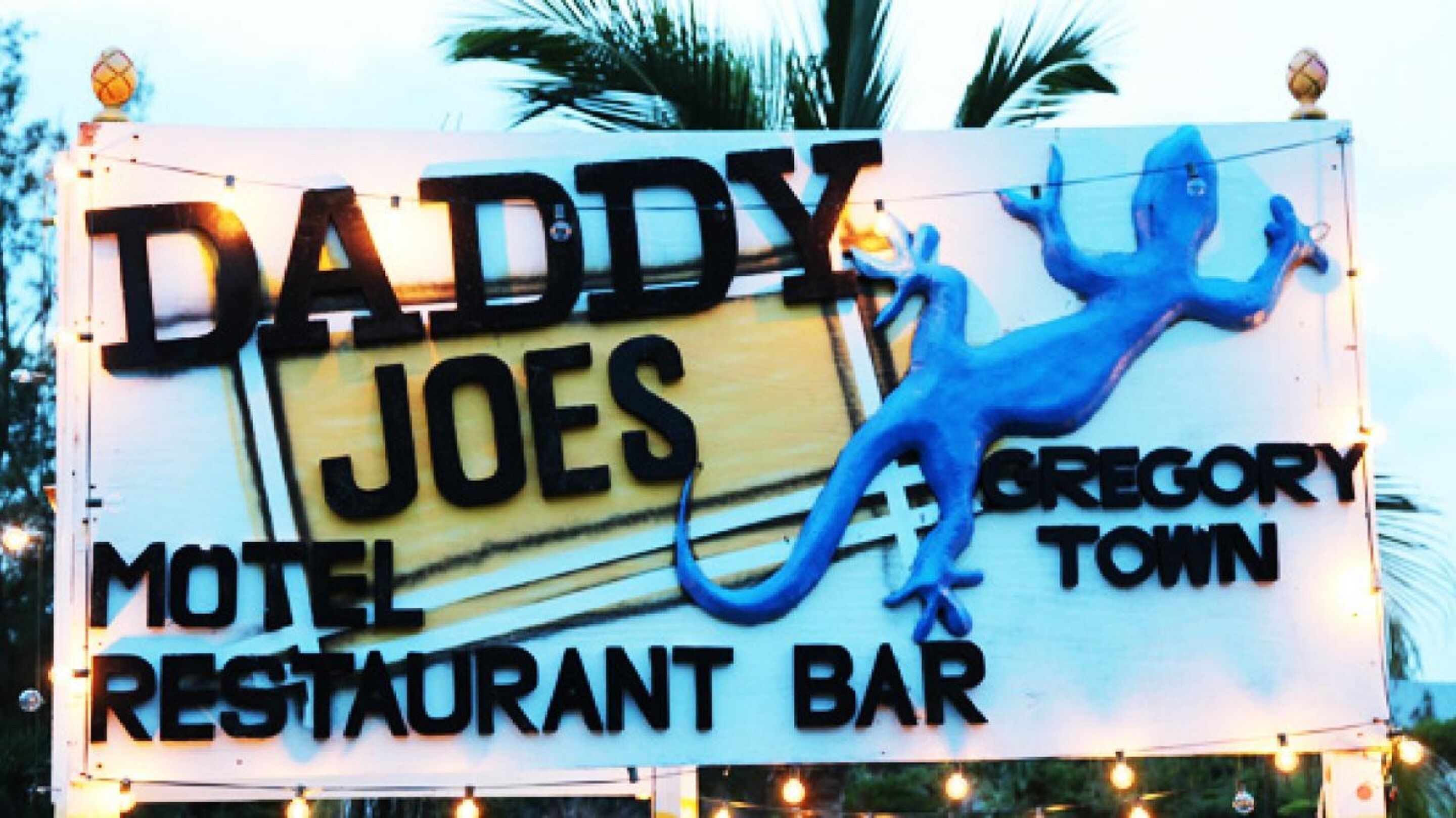 A sign for 'Daddy Joe's Motel Restaurant Bar' with a blue lizard graphic.
