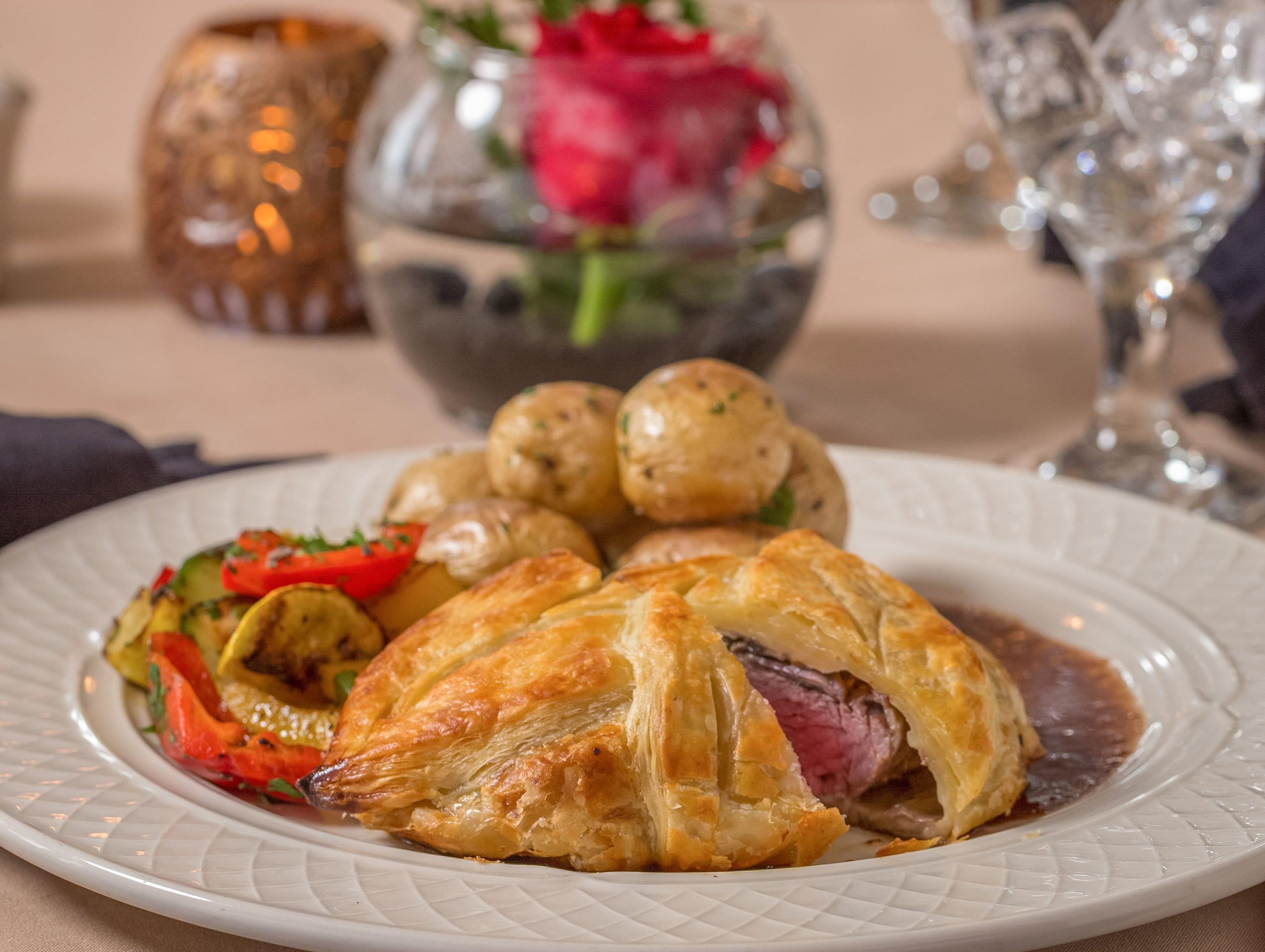 A plate of food with a pastry, vegetables, and meat.