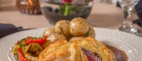 A plate of food with a pastry, vegetables, and meat.