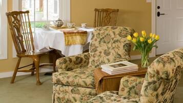 A room with floral-patterned chairs, a table with a white tablecloth, and a door.