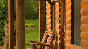 A log cabin with a wooden porch, a door, and a window. - Goldmoor Inn (Galena)