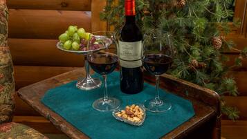 Una mesa de madera con una botella de vino, copas, un plato de nueces y un bol de uvas.