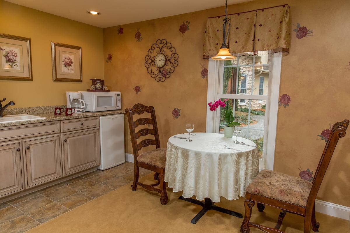 A kitchen with a dining table, chairs, a microwave, and a coffee maker.