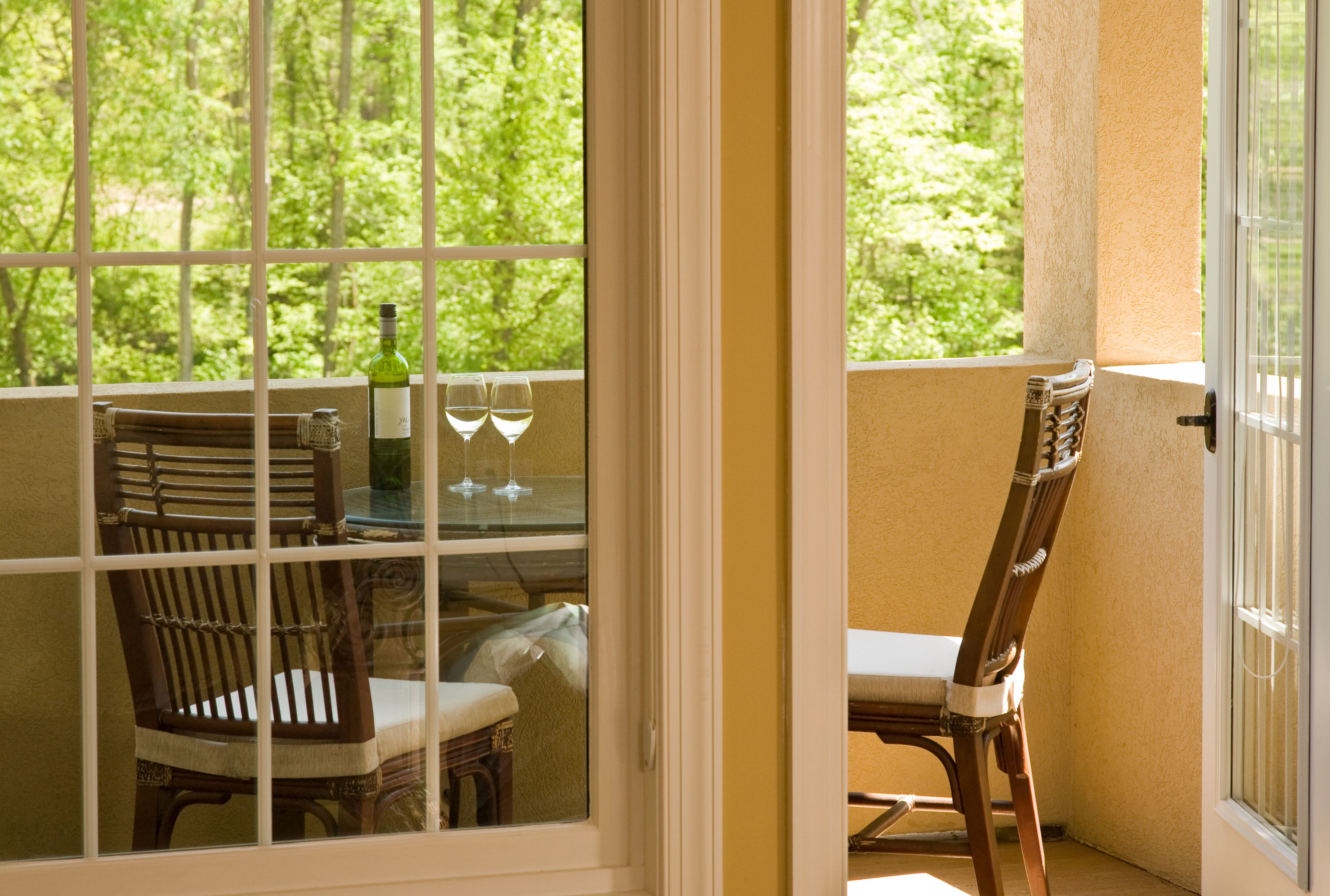 Un balcon avec une table, des chaises et une bouteille de vin.