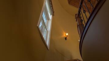 A staircase with a wooden handrail and a light fixture on the wall.