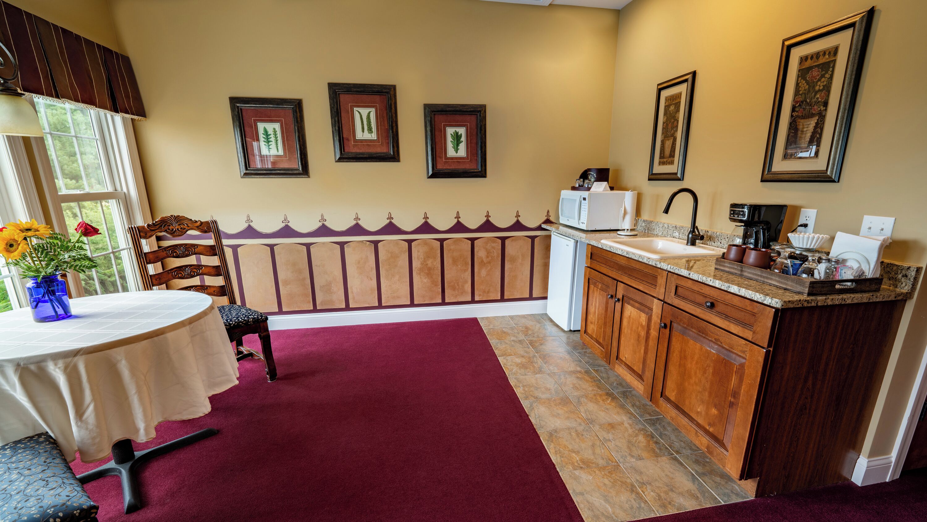 A kitchen with a marble countertop, wooden cabinets, a sink, and a microwave.