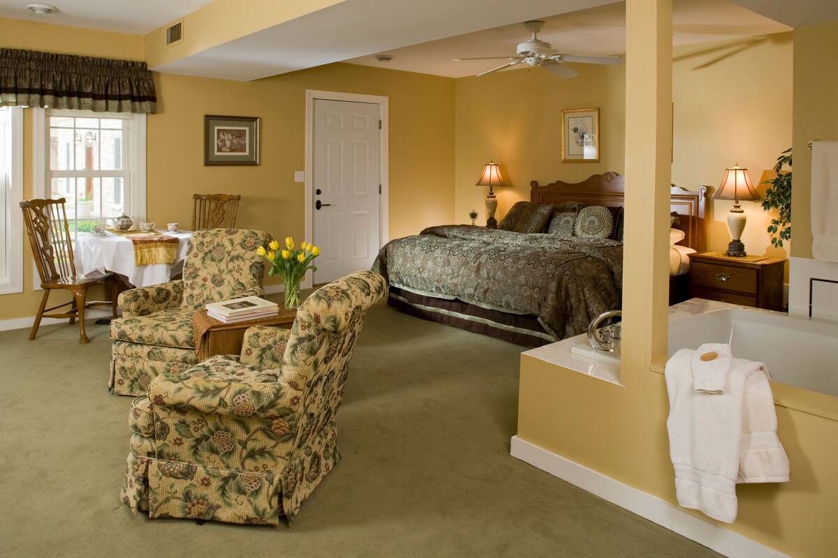 A bedroom with a bed, bedside table, lamp, and a chair.