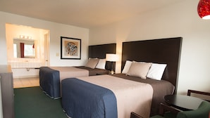 Une chambre d’hôtel avec deux lits, un bureau, une chaise, un miroir et une œuvre d’art encadrée au mur.