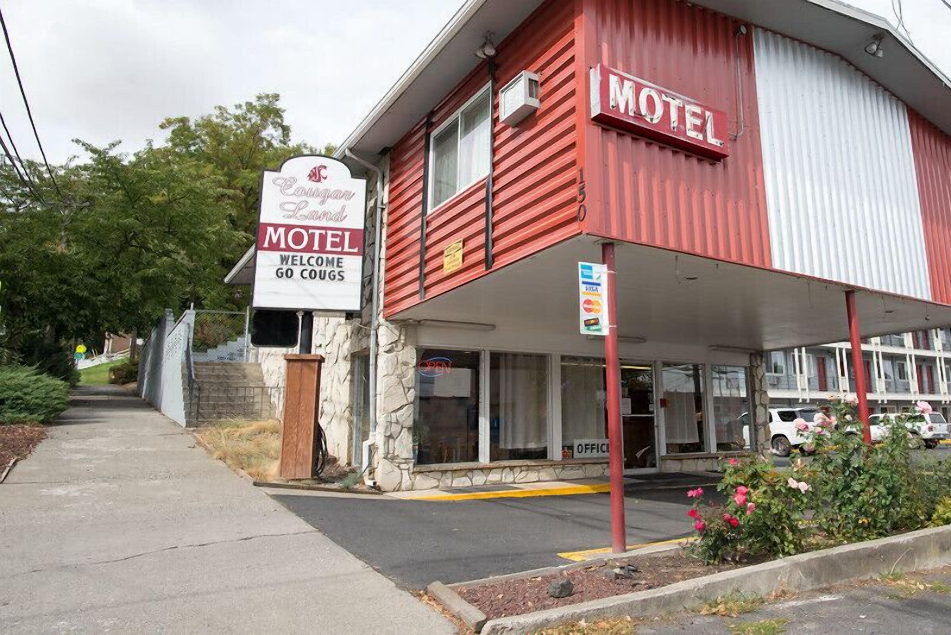 A red motel with a sign that reads "Cogan Land Motel Welcome Go Cugs."