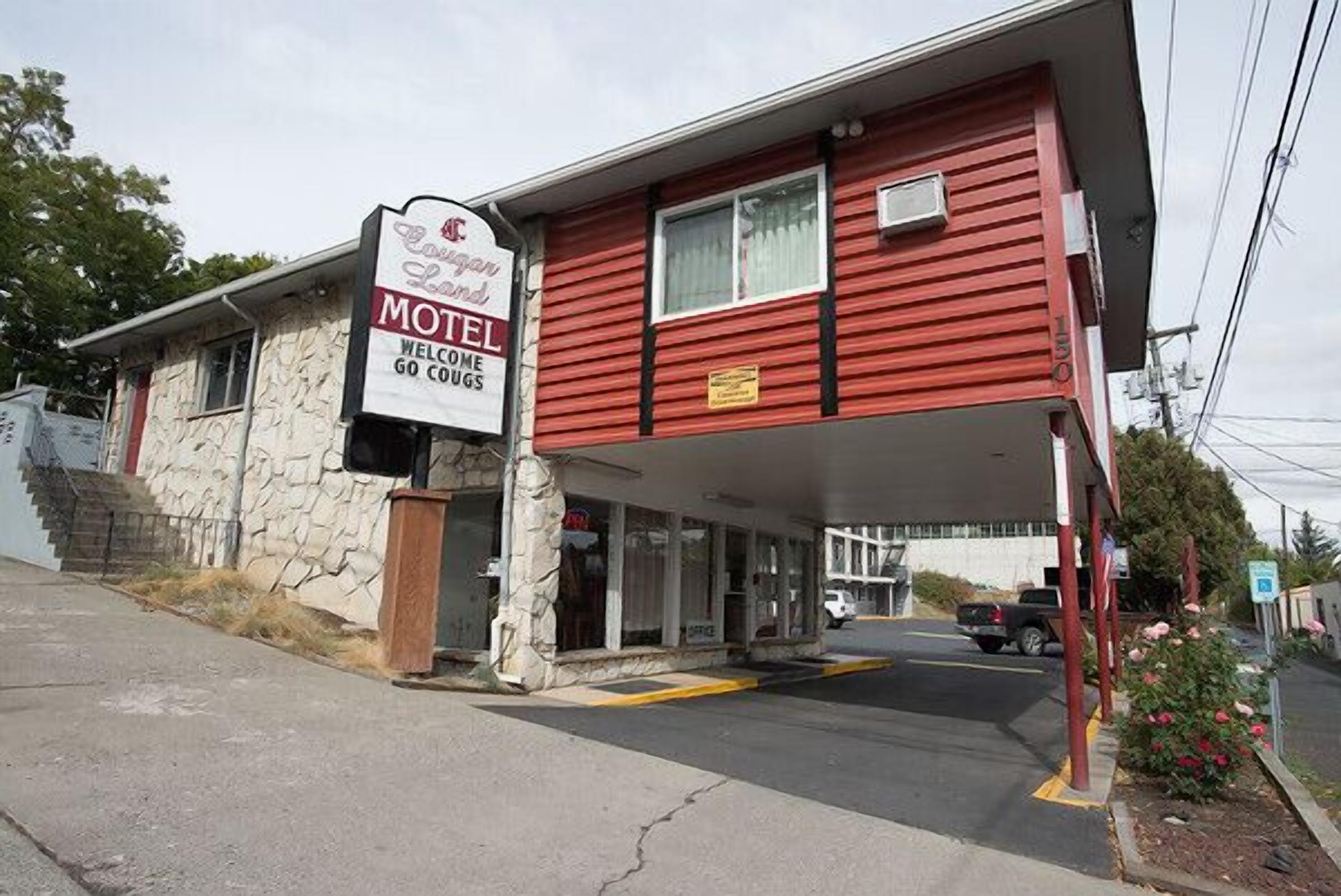 A red motel with a stone facade and a sign that reads "Welcome Go Clogs."