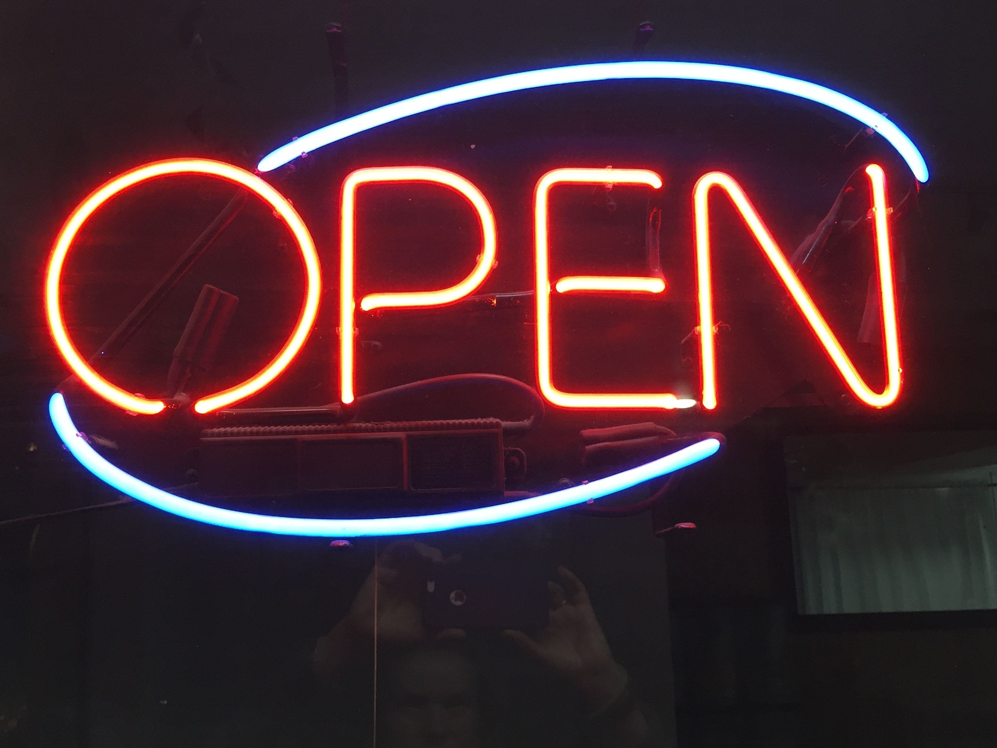 Une enseigne au néon avec le mot « OUVERT » écrit en lettres rouges et bleues.