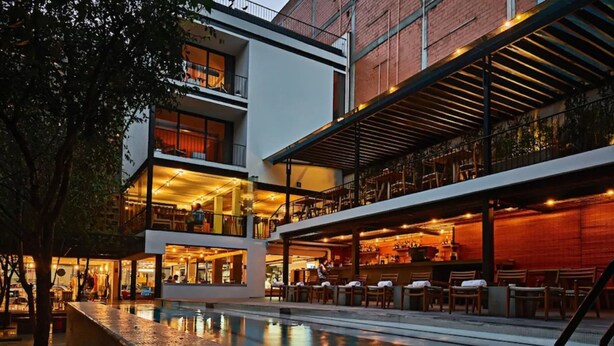 Un hotel moderno con piscina, zona de estar al aire libre y bar.