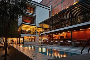 Un hotel moderno con piscina, zona de estar al aire libre y bar.