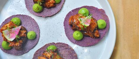 A plate with four purple-colored food items, each garnished with green olives and a pinkish slice of radish.