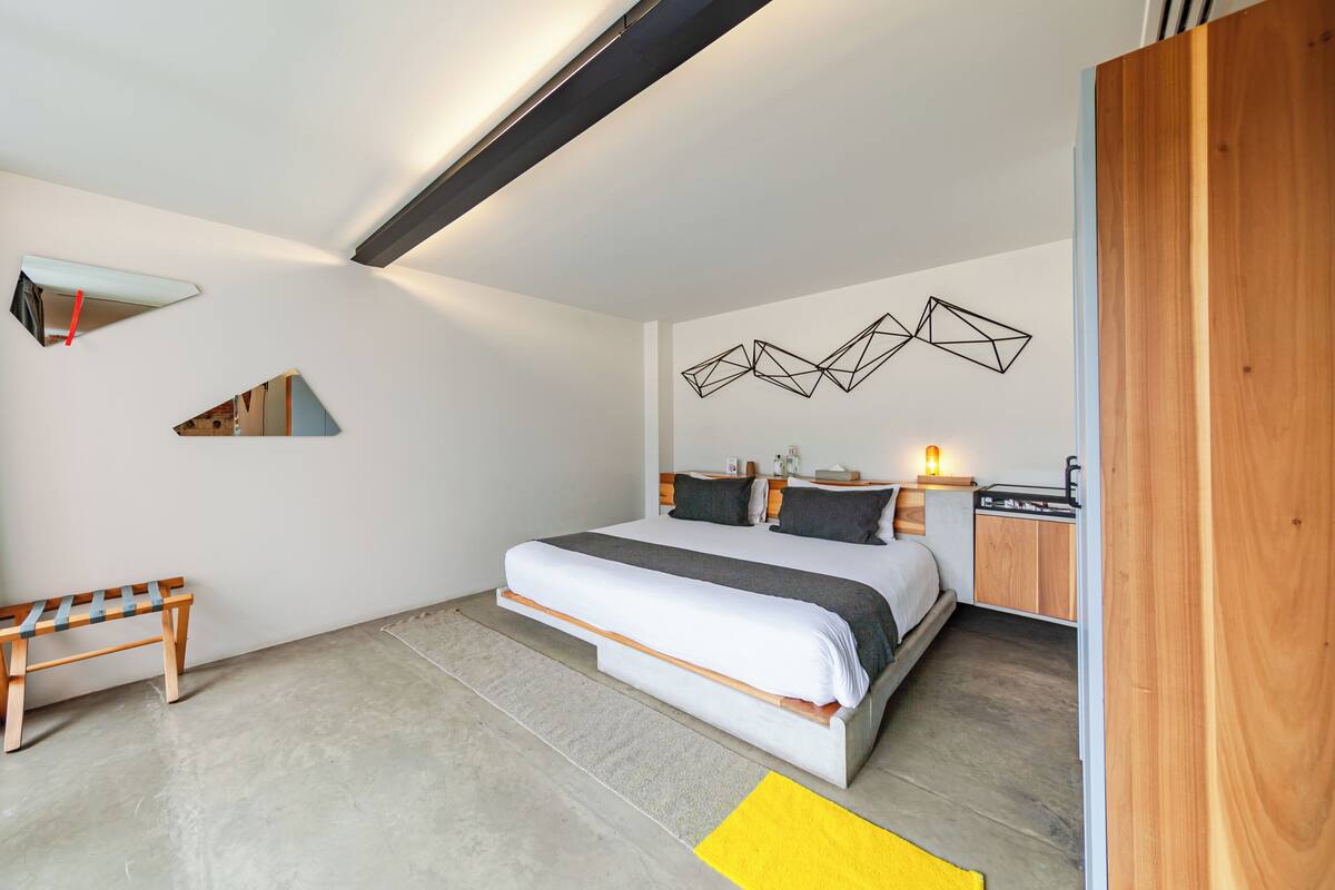 A modern bedroom with a bed, bedside table, and a bench.