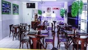 Un restaurante con varias mesas y sillas, una zona de bar y plantas decorativas.