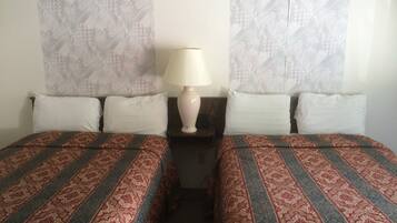 A double bed with patterned bedding, a bedside table with a lamp, and patterned curtains.