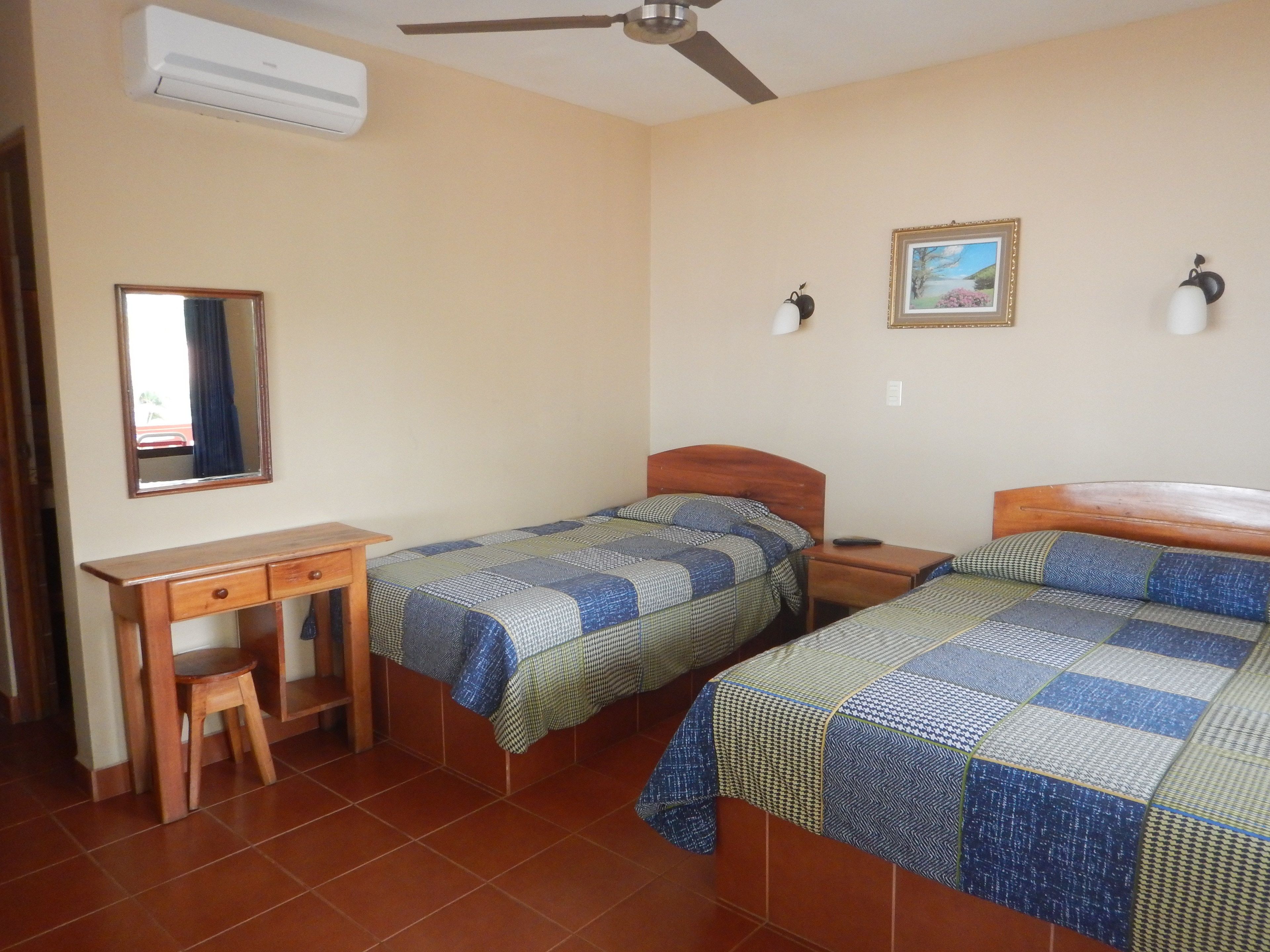A bedroom with two beds, a desk, and a chair.