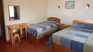 A bedroom with two beds, a desk, and a chair.