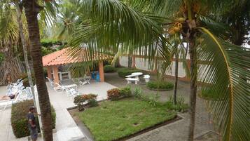 A courtyard with palm trees, a covered seating area, and a small lawn.